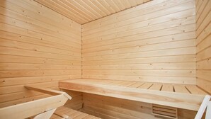 A sauna room with wooden walls and benches. - Stylish Nordic 2BR Apartment with Sauna (Kuopio)