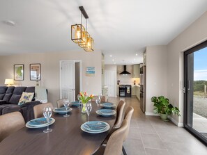 Een moderne eetruimte met een donker houten tafel voor zes personen, omringd door lederen stoelen.