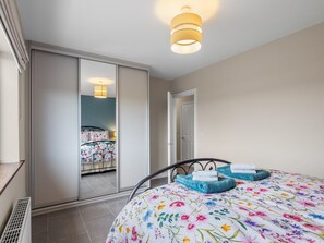 Un dormitorio con cama, puerta corredera y lámpara en el techo.