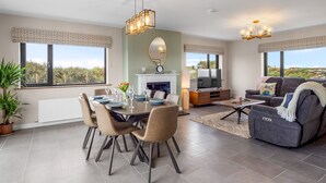 Una sala de estar moderna con comedor, ventanas amplias y chimenea.
