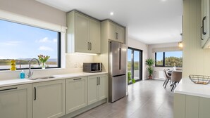 Una cocina moderna con armarios verde claro, electrodomésticos de acero inoxidable y un amplio ventanal con vistas al exterior.