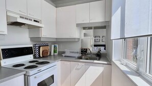 Una cucina moderna con mobili bianchi, forno integrato e una finestra.