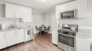 A modern kitchen with white cabinets, a stainless steel stove, and a microwave.