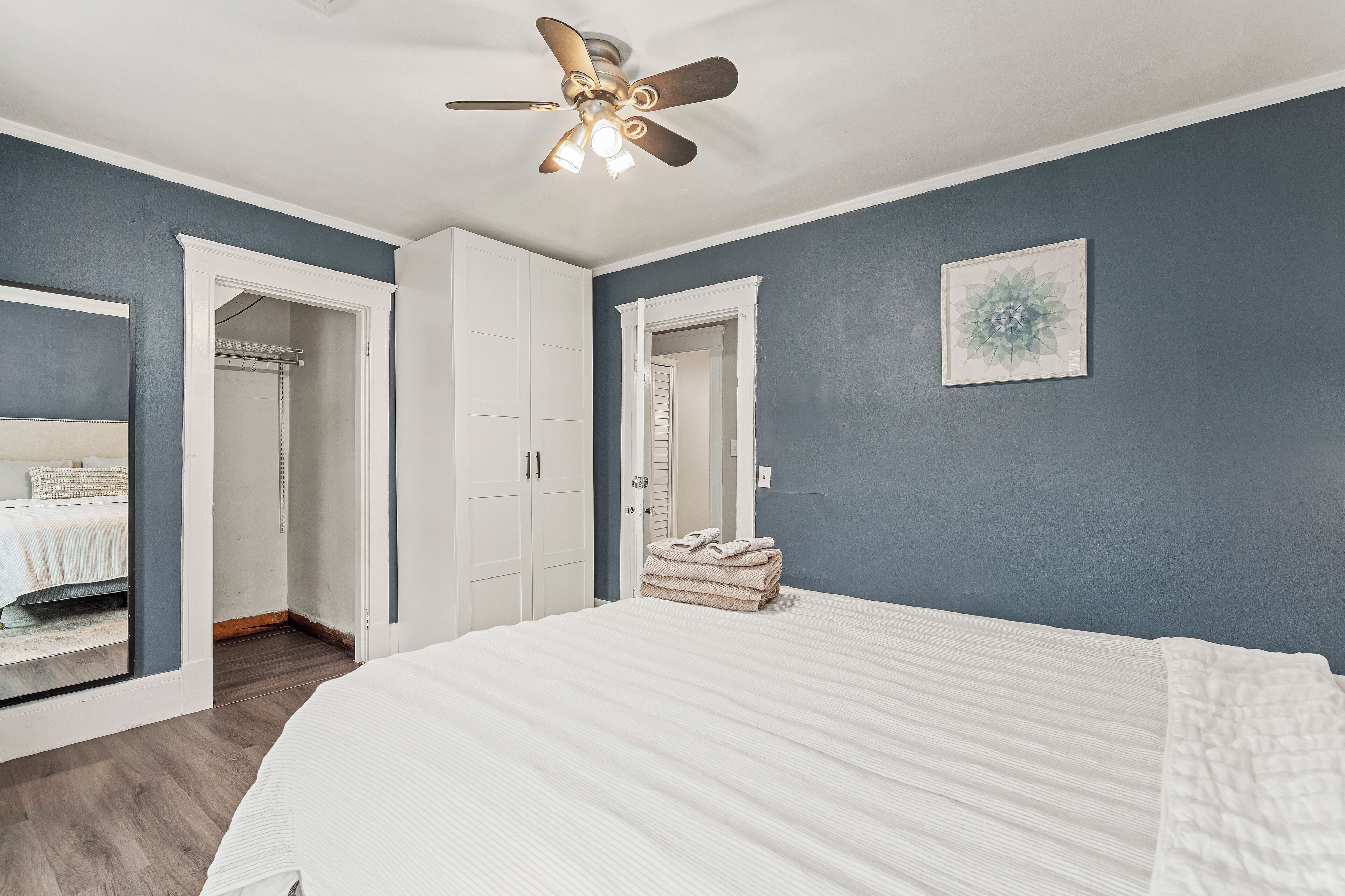 A bedroom with a large bed, a ceiling fan, and a wardrobe.