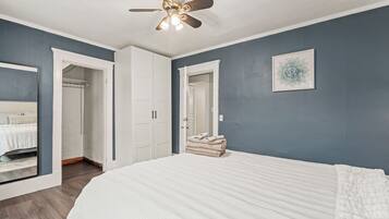 A bedroom with a large bed, a ceiling fan, and a wardrobe.