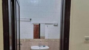 Ein kleines Badezimmer mit einem weißen Waschbecken, einer Toilette und einem Spiegel über dem Waschbecken.