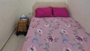 Ein kleiner, schmaler Raum mit einem Bett, einem kleinen Tisch und einer an der Wand befestigten Klimaanlage.