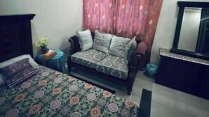 Un dormitorio con cama, sofá, una mesita con una planta y un espejo en la pared.