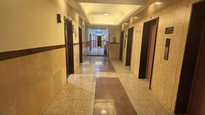 A long, narrow hotel corridor with a tiled floor and walls, featuring doors and a ceiling light. - Al Farabi Towers Hotel (Makkah)