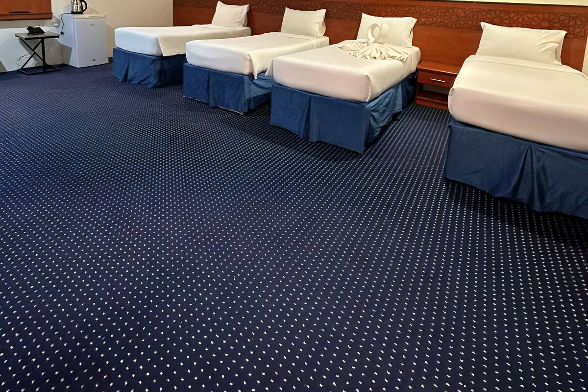 Een hotelkamer met vier bedden, een bureau met waterkoker en een televisie aan de muur.