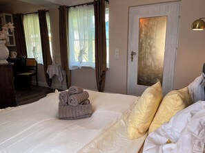 Un lit bien fait, avec des serviettes pliées, une table de chevet, une chaise et une porte dotée d’un miroir.