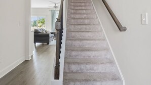 A staircase with a handrail, carpeted steps, and a ceiling fan. - Sleeps 6 - 12 min from Fort Jackson - EV Charger & Pet Friendly! (Elgin)