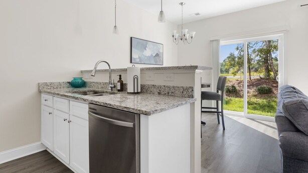 A modern kitchen with a granite countertop, stainless steel appliances, and a view of the outdoors through a sliding glass door. - Sleeps 6 - 12 min from Fort Jackson - EV Charger & Pet Friendly! (Elgin)