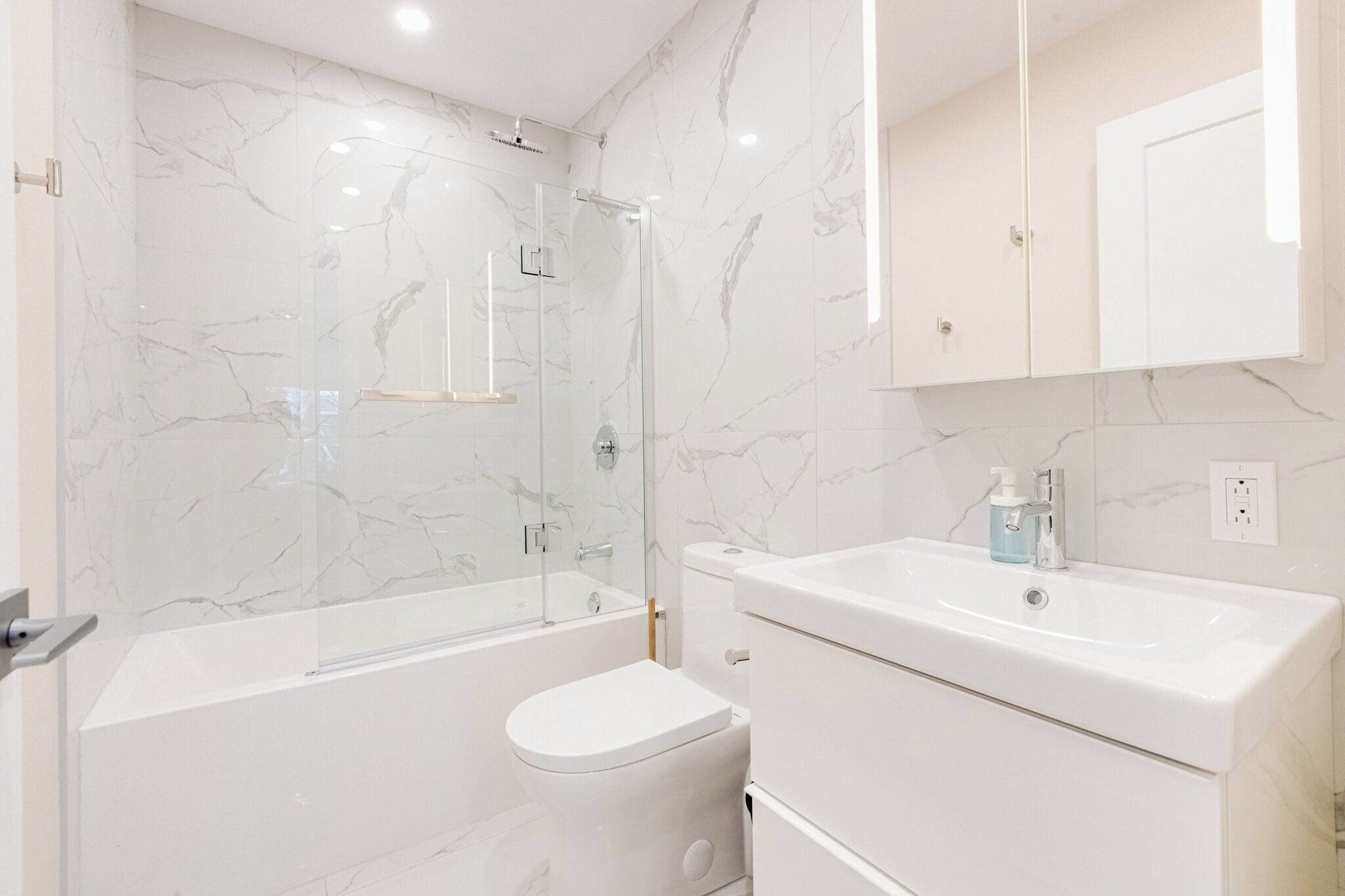 Un bagno moderno con cabina doccia in vetro, un WC bianco e un mobile lavabo.