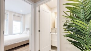 Una camera da letto con un letto, un bagno con un lavandino e una pianta.