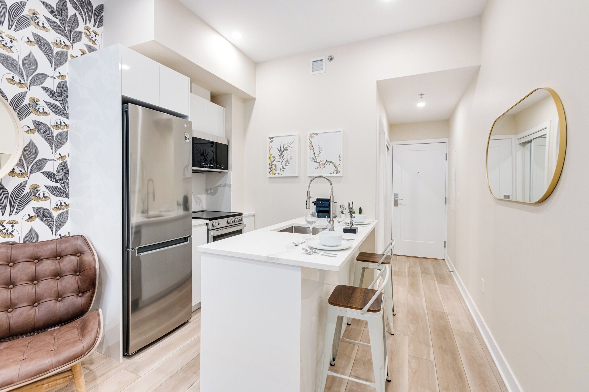 Een moderne keuken met witte kastjes, een roestvrijstalen koelkast en een centraal eiland met barstoelen.