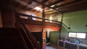 A spacious kitchen with a high ceiling and a wooden staircase leading to an upper level.