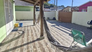 A covered outdoor area with a hammock, a chair, and cleaning supplies.