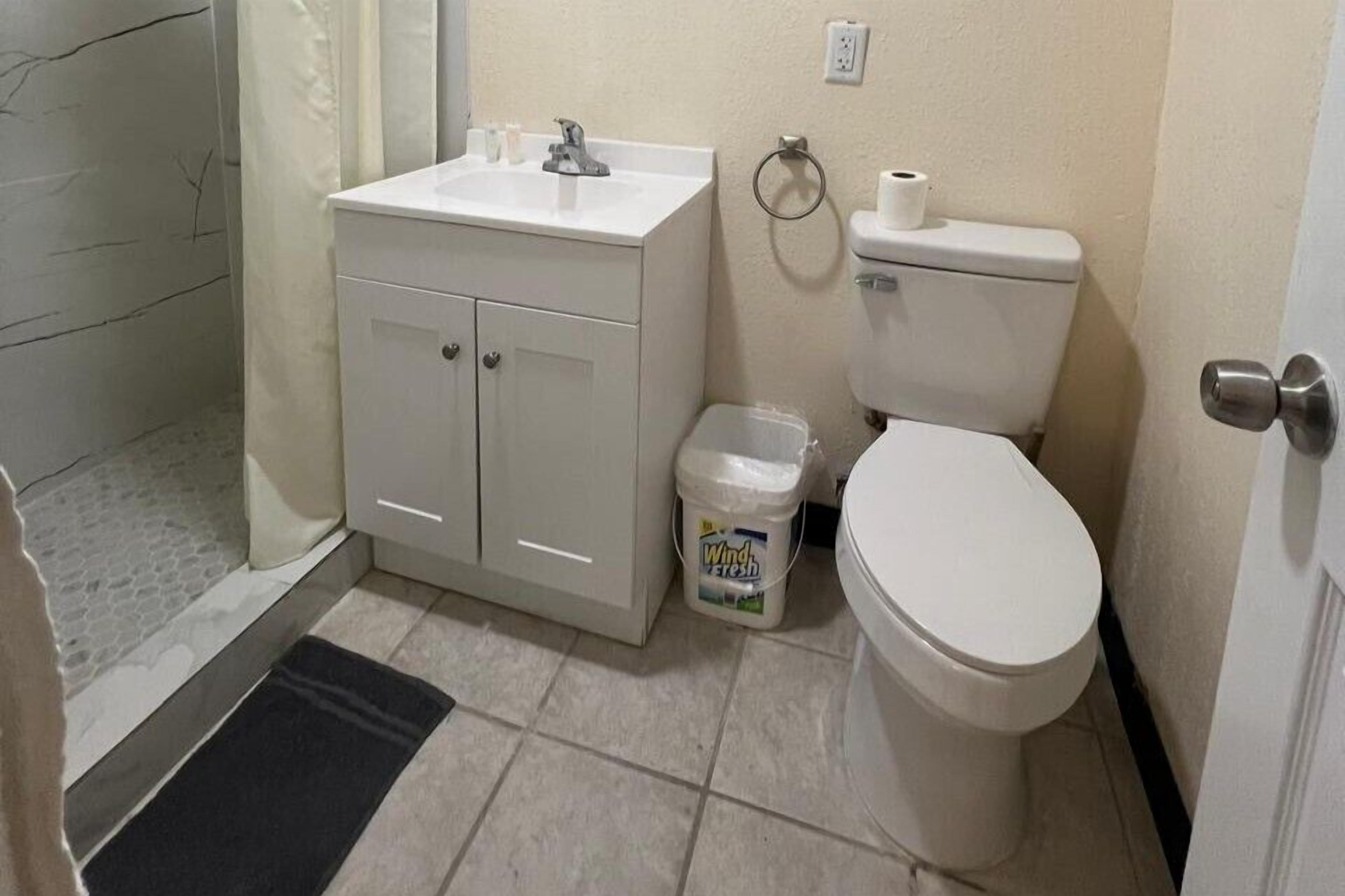 Ein Badezimmer mit Waschbecken, Toilette und einer kleinen Mülltonne.