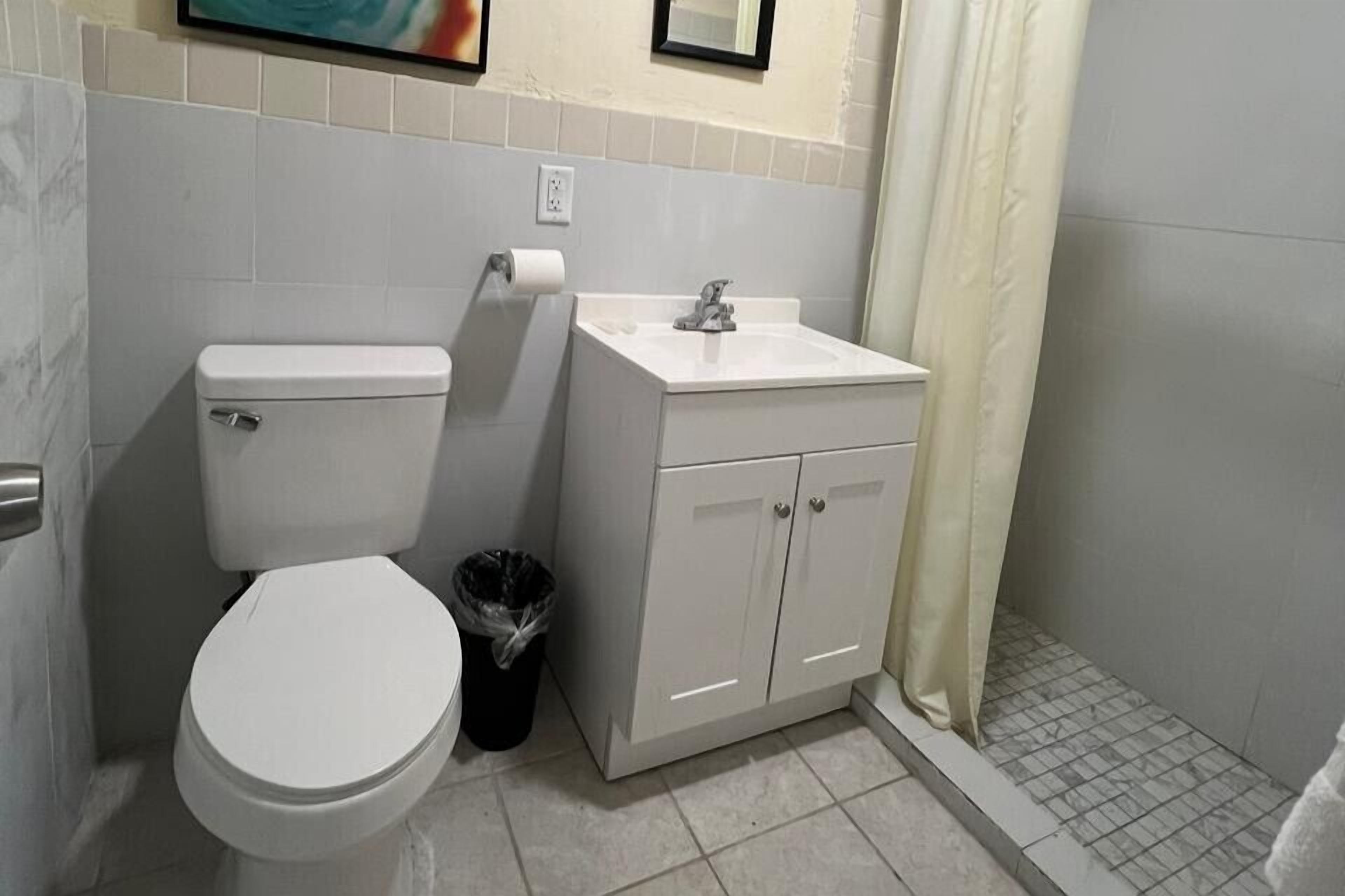 A small bathroom with a toilet, sink, and shower curtain.