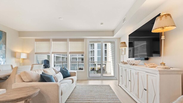 Un salon moderne avec un canapé, une table basse et un téléviseur. Il y a un balcon avec une balustrade et une vue sur la ville.