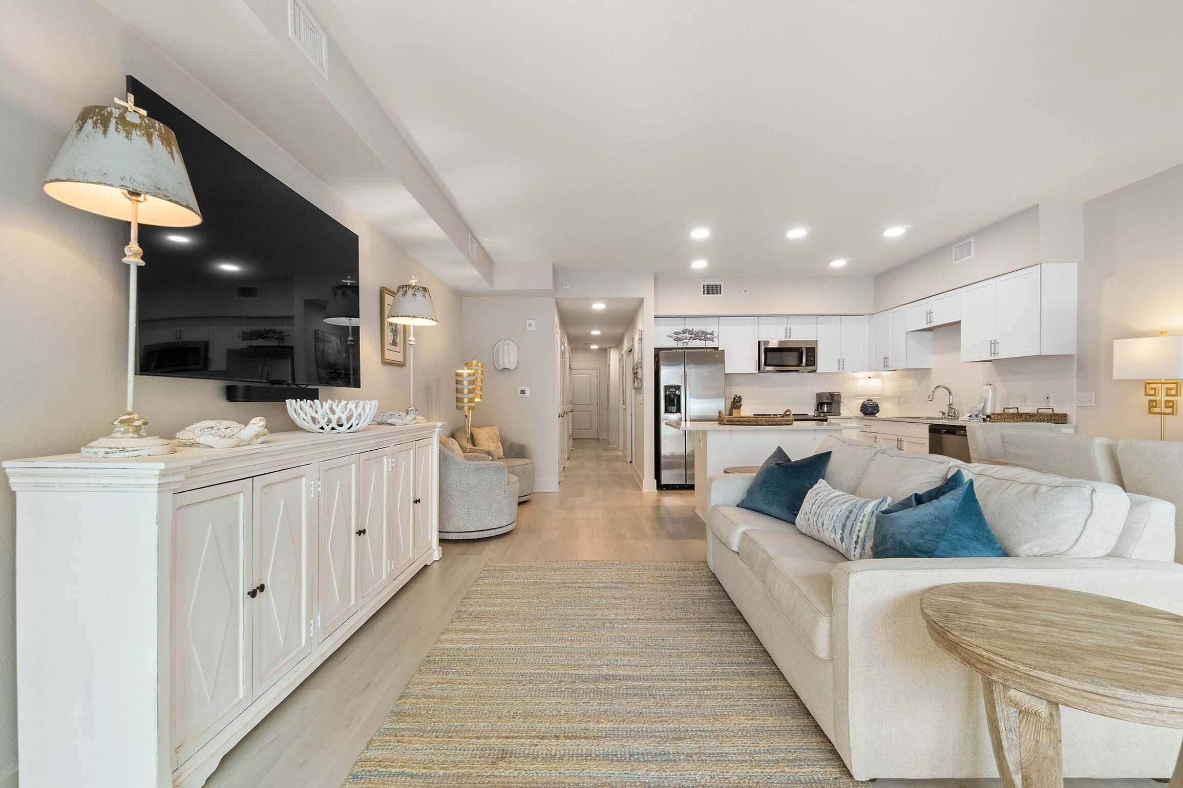 Un salon moderne avec un canapé blanc, une table basse et un téléviseur fixé au mur.