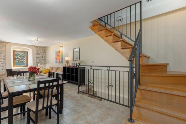 Un comedor con una escalera de madera y una pared de piedra.