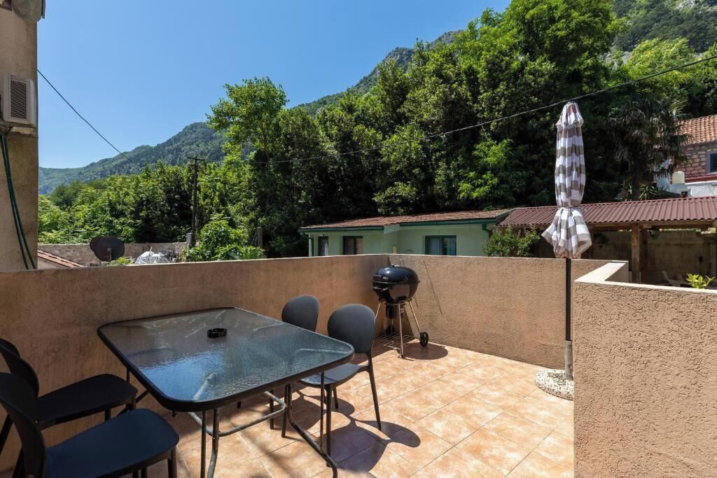 A patio with a table and chairs, a grill, and an umbrella.