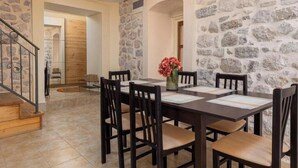 Un coin repas agrémenté d’un mur en pierre, d’un escalier en bois et d’une table dressée pour quatre personnes.
