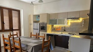 Una cocina compacta con comedor, que incluye un horno empotrado, una estufa y un refrigerador.