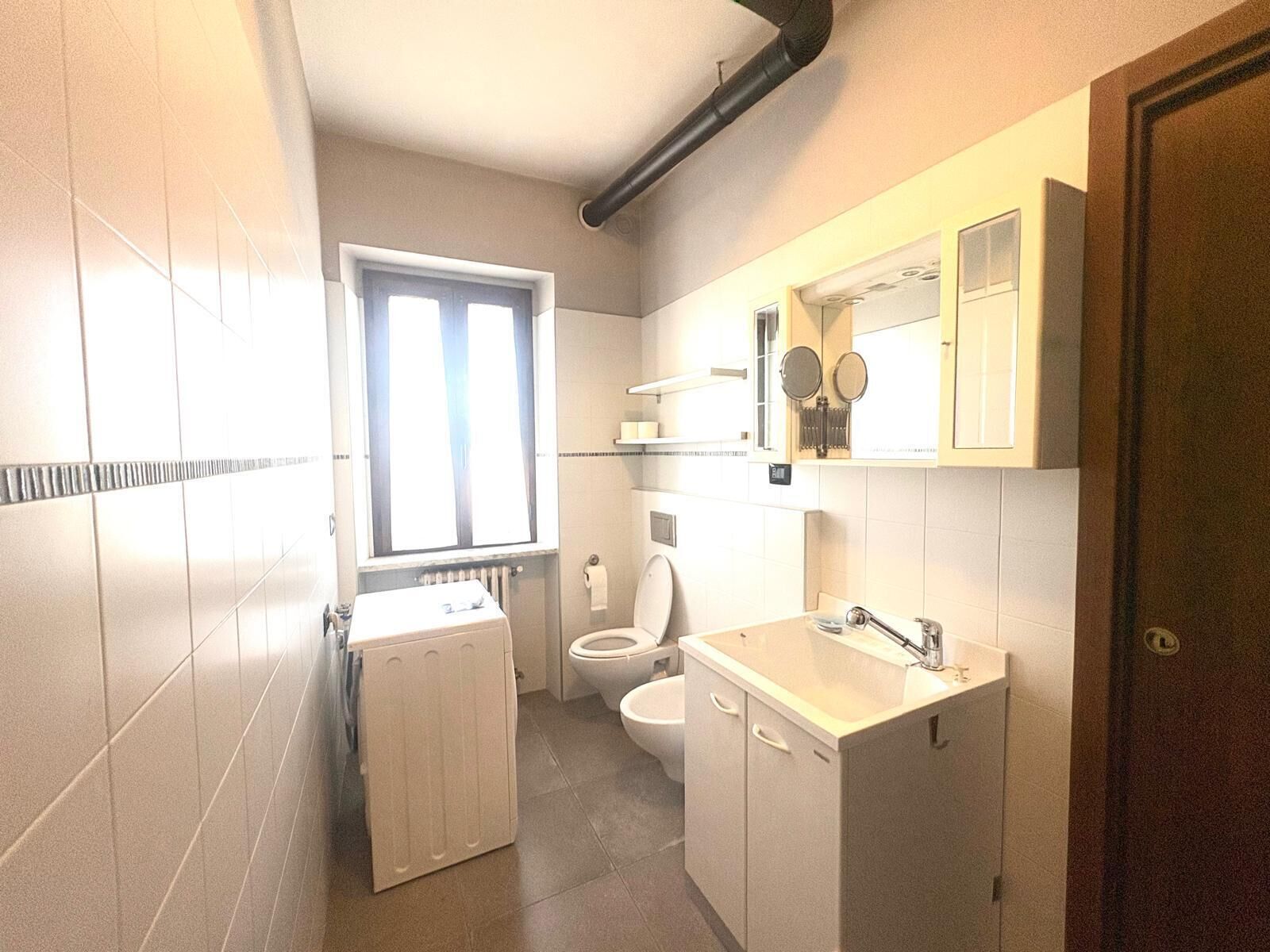 Ein kleines Badezimmer mit Toilette, Waschbecken und Fenster.
