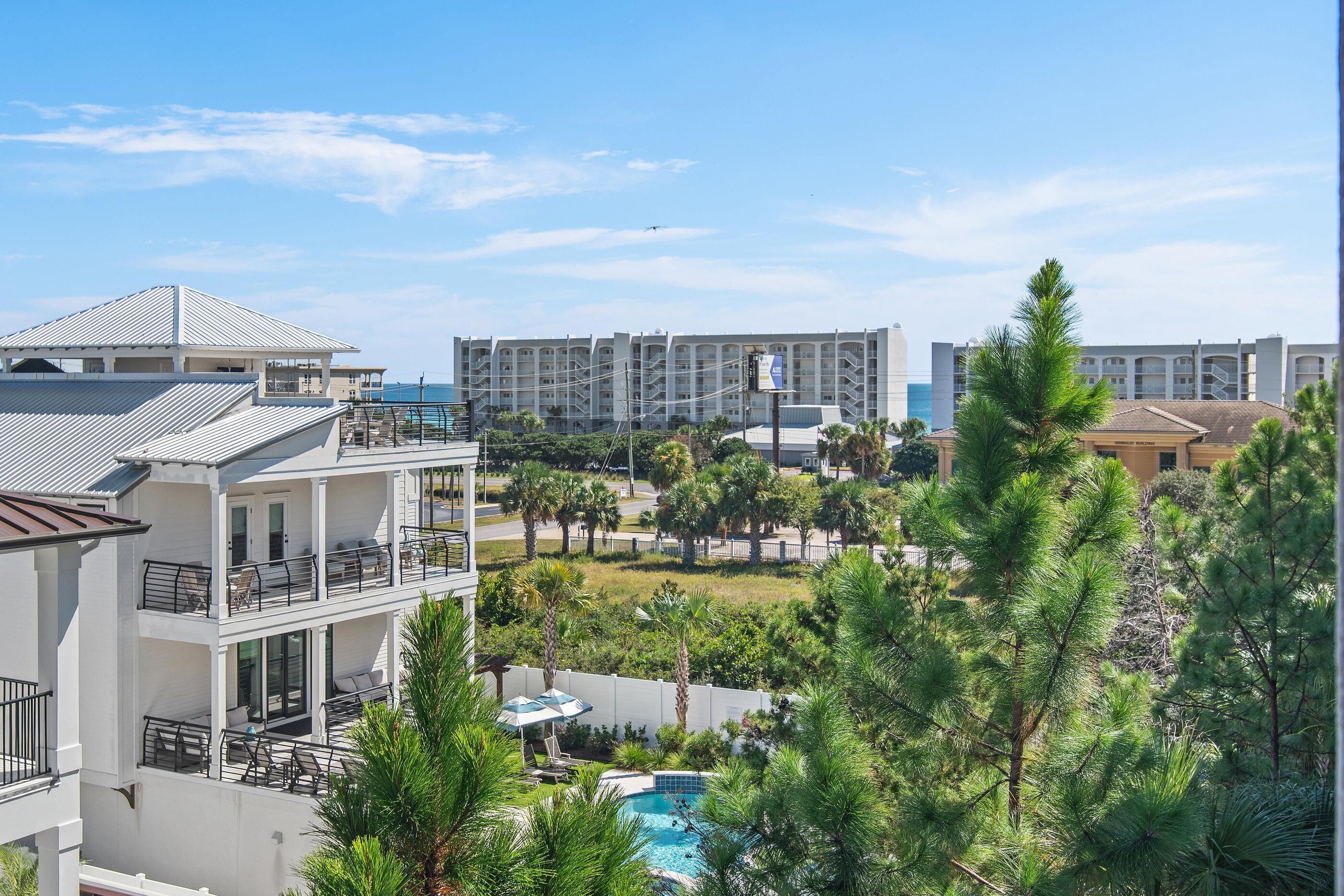 A multi-story hotel with balconies, a swimming pool, and surrounding greenery.