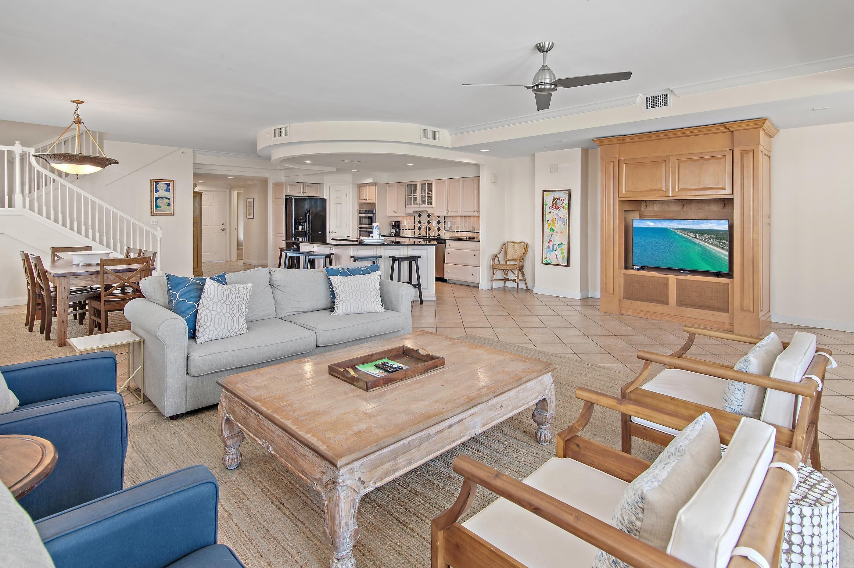A spacious living area with a dining set, a sofa, a coffee table, and a TV mounted on a wooden cabinet.