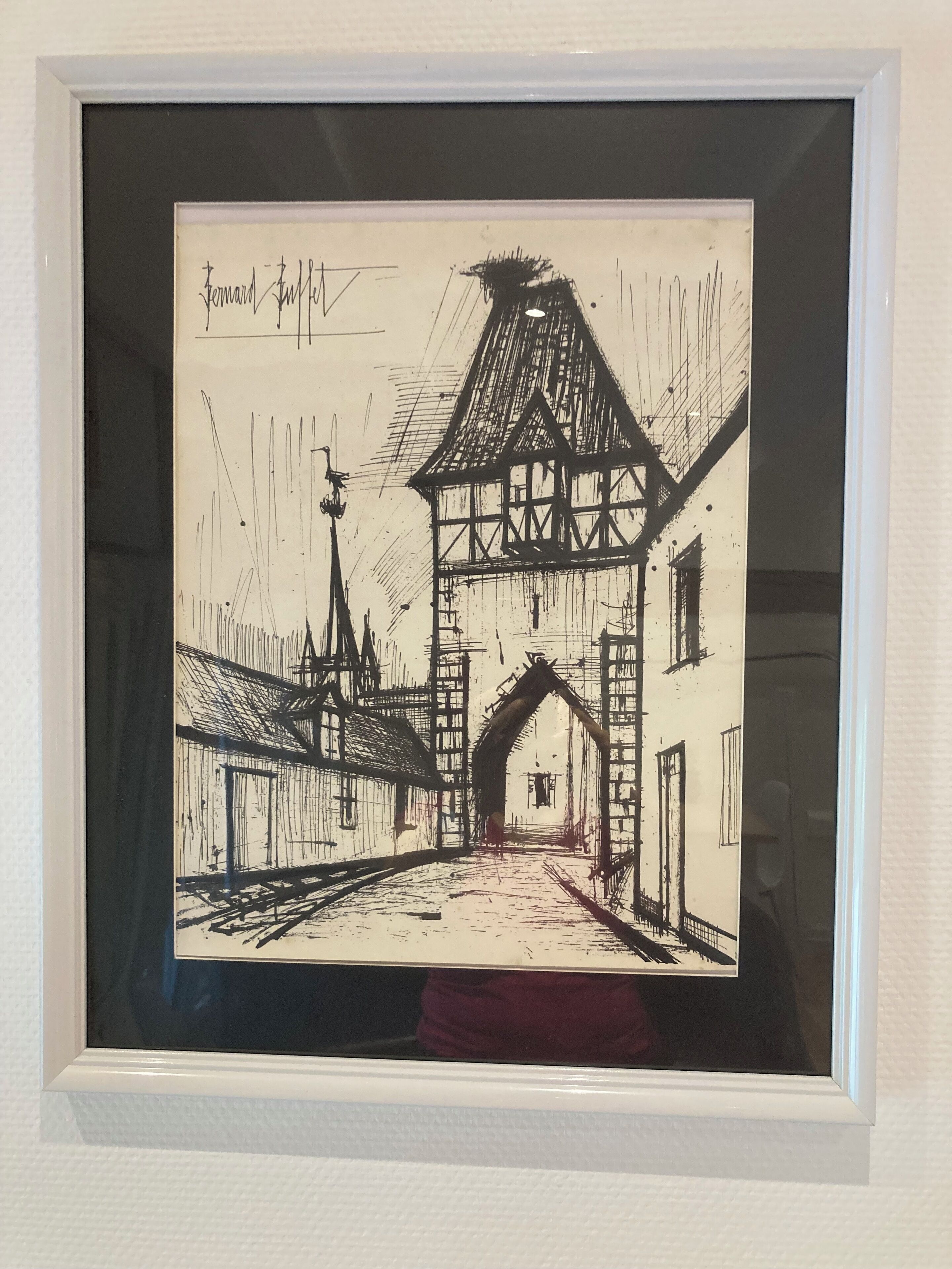 Eine gerahmte Schwarz-Weiß-Zeichnung einer Straßenszene mit einem Gebäude und einem Turm.