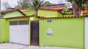 Una casa verde con una puerta de garaje blanca, un portón de madera y un letrero pequeño en la pared.