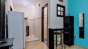 Una cocina compacta con refrigerador, un pequeño comedor con dos sillas y un salpicadero de azulejos.
