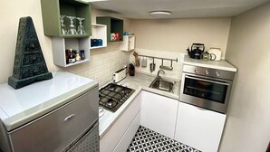 Eine kleine Küche mit Gaskochfeld, Backofen und Kaffeemaschine auf der Arbeitsfläche.