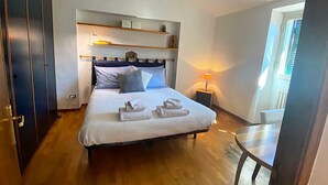 Ein Schlafzimmer mit Bett, Nachttischen, einem Kleiderschrank und einem Fenster.