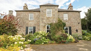 A stone building with a symmetrical facade, two chimneys, and a central entrance. - Balsaggart Farm (Maybole)