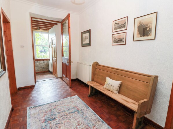 A hallway with a wooden bench, a patterned rug, and framed pictures on the wall. - Balsaggart Farm (Maybole)