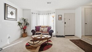 Ein Wohnzimmer mit einer Couch, einem Couchtisch und einer Topfpflanze.