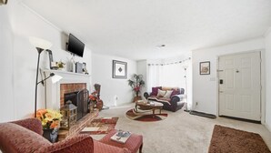 Ein Wohnzimmer mit Kamin, einer Couch, einem Couchtisch und einem Fernseher.