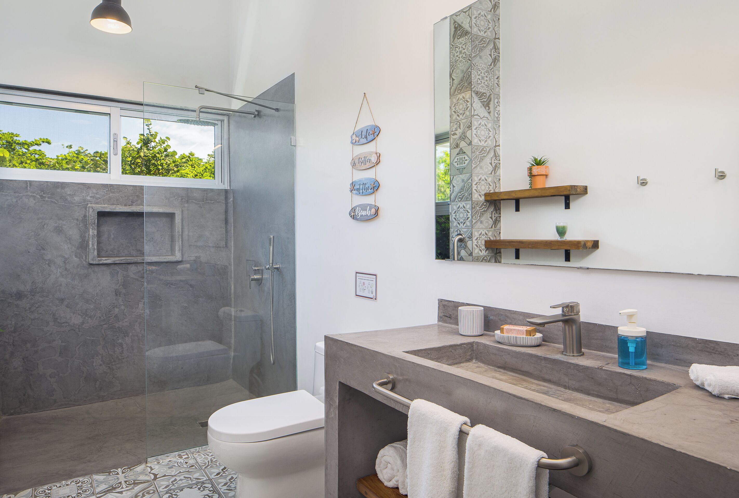 A modern bathroom with a glass shower enclosure, a large mirror, and a vanity with a sink and towel rack.