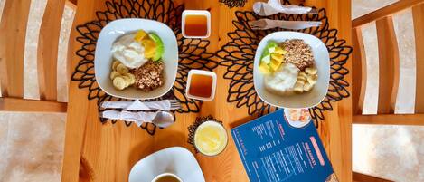 A breakfast setting with two plates of food, a menu, and a cup of tea on a wooden table.
