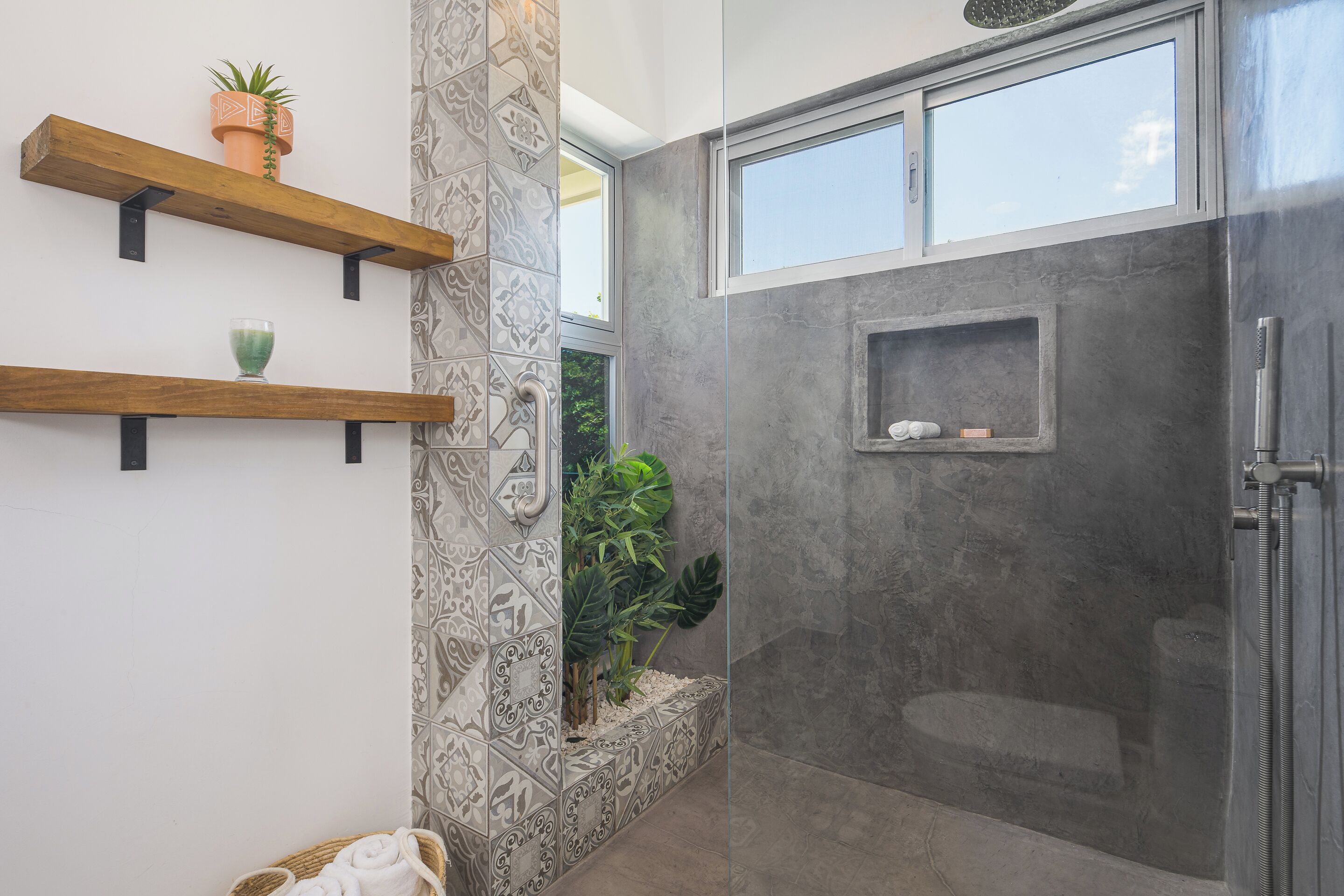 Een moderne badkamer met een douche, een plant in pot en een decoratieve wand van tegels.