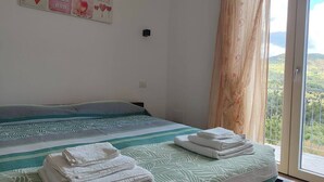 Een slaapkamer met een bed, uitzicht op de omgeving en een decoratie aan de muur.