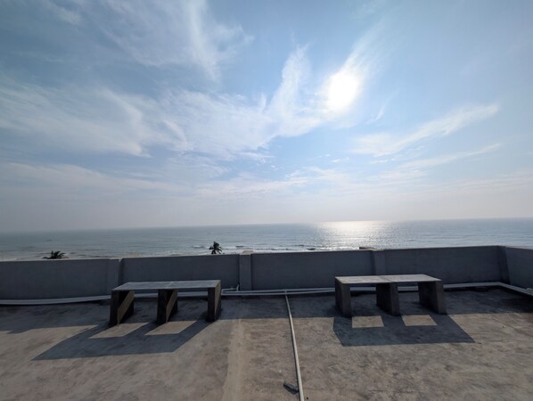 A rooftop terrace with concrete benches and a view of the sea.