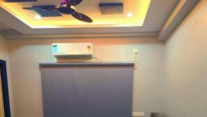 A bedroom with a bed, a bedside table, a ceiling fan, and an air conditioning unit.