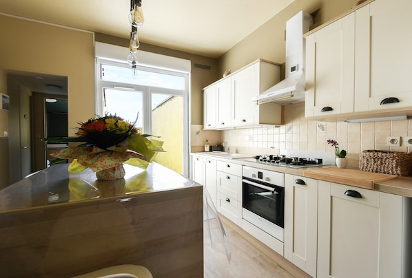 A modern kitchen with white cabinets, a central island, a stove, and a sink.