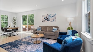 A spacious living room with a large window, a dining area, and a sofa.